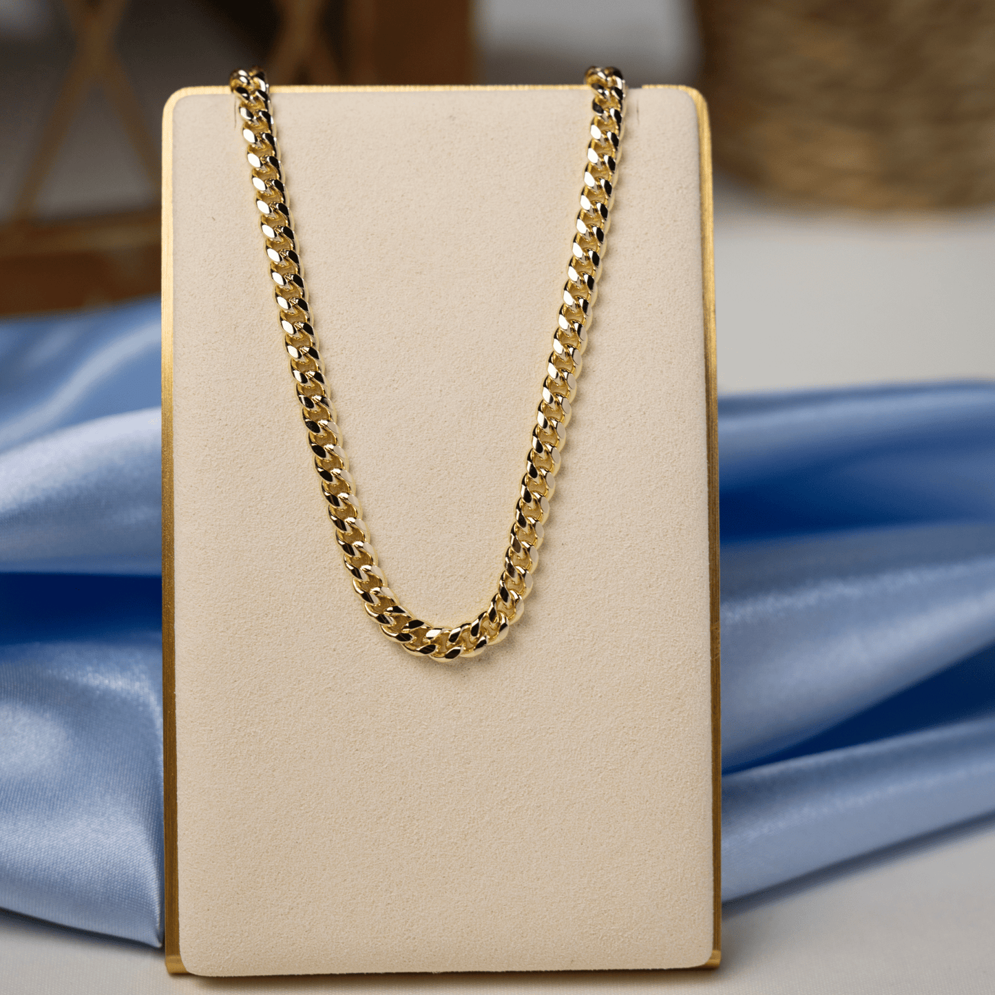 Gold Cuban link chain necklace displayed on a jewelry stand, highlighting its polished finish and classic curb link design.