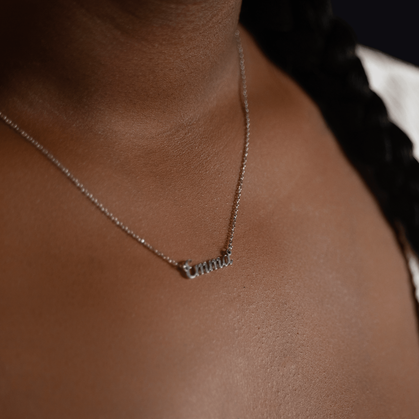 Woman wearing a custom silver name necklace engraved with the name Emma