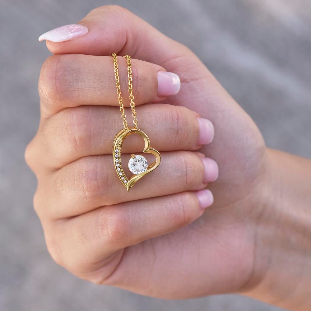 Woman holding gold heart cubic zirconia pendant necklace on delicate chain