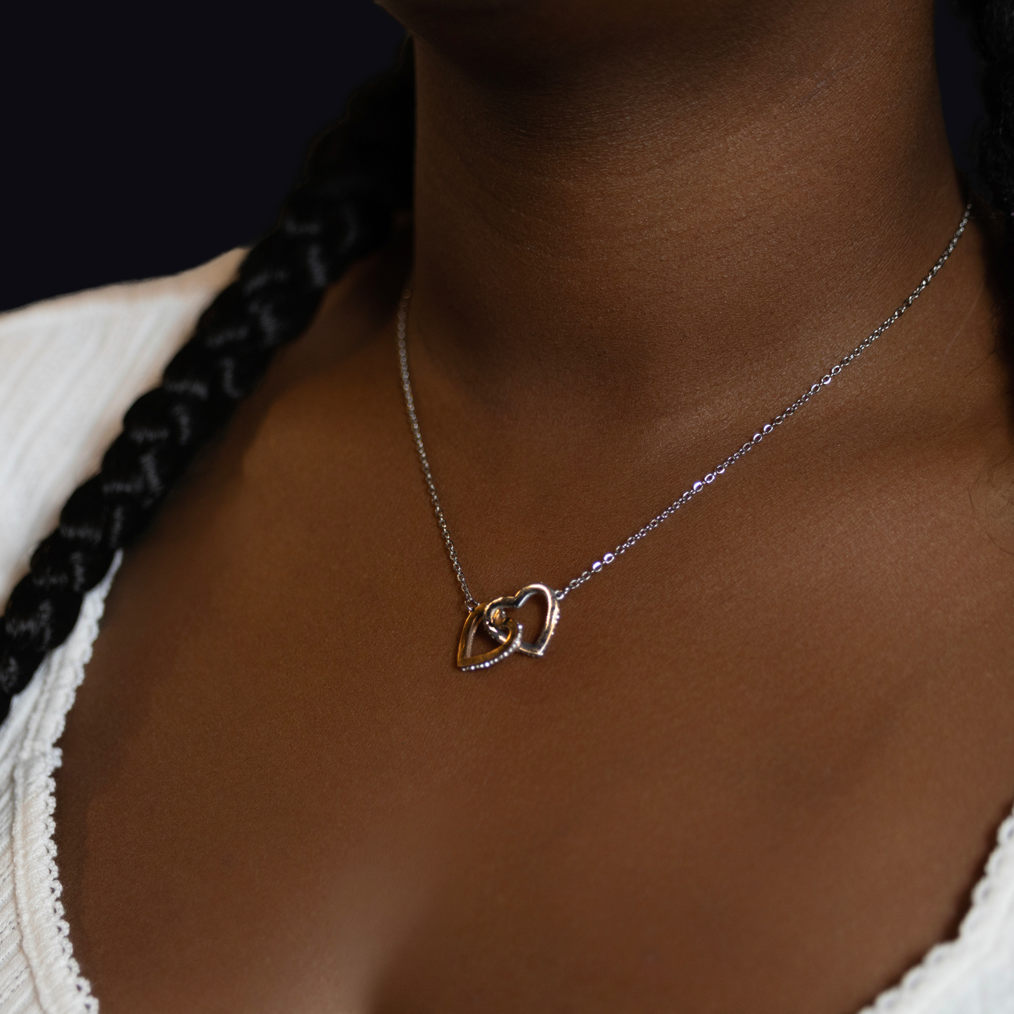  delicate silver chain necklace with two interlocking heart pendants, one rose gold and one silver