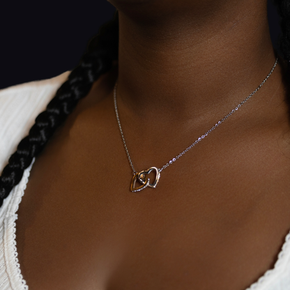  delicate silver chain necklace with two interlocking heart pendants, one rose gold and one silver