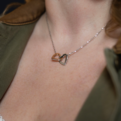  delicate silver chain necklace with two interlocking heart pendants, one rose gold and one silver