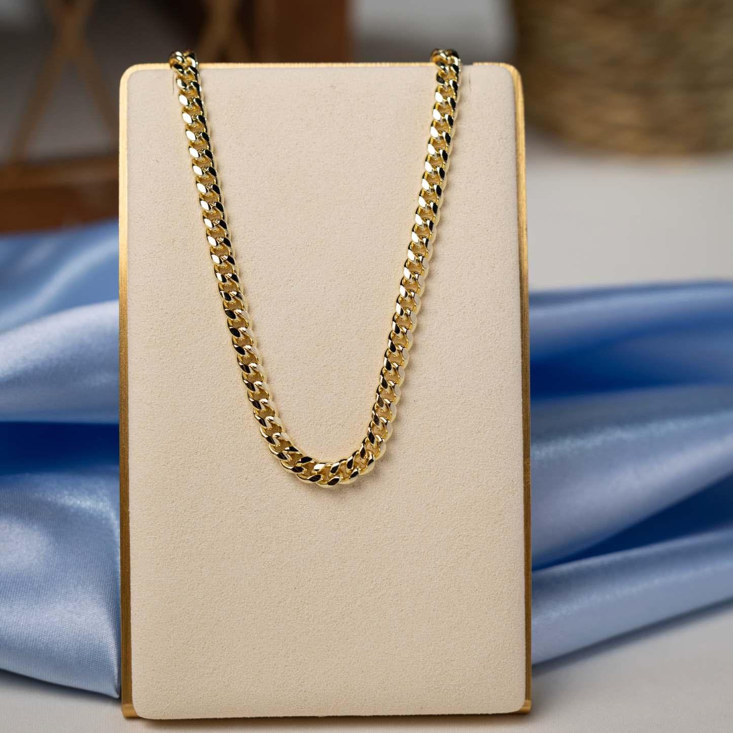 Gold Cuban link chain necklace displayed on a jewelry stand, highlighting its polished finish and classic curb link design.