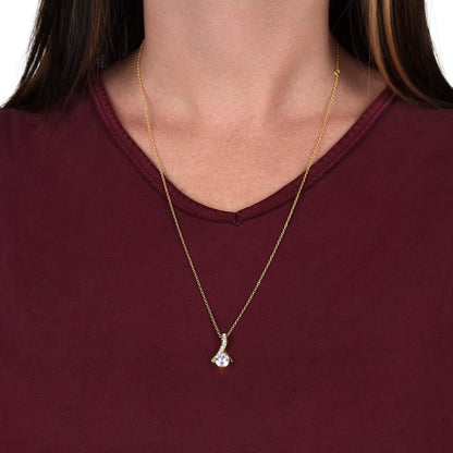 Woman wearing a gold pendant necklace featuring a curved pavé accent and round solitaire stone, styled with a burgundy top.