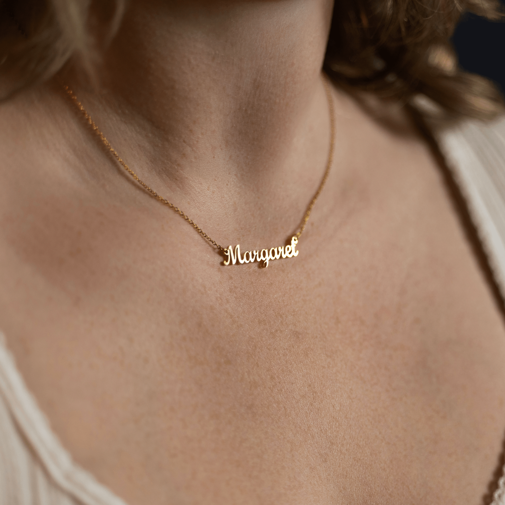 woman wearing a personalized gold name necklace featuring the name Margaret in elegant script on a delicate chain