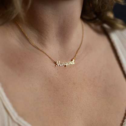 Close-up of a woman wearing a personalized gold name necklace featuring the name Margaret in elegant script on a delicate chain