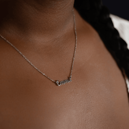Woman wearing a custom silver name necklace engraved with the name Emma