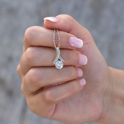 Elegant silver pendant necklace featuring a curved pavé-set accent with a round brilliant-cut solitaire stone, held delicately in hand with soft pink manicured nails.
