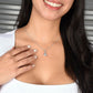 Smiling woman wearing a delicate silver pendant necklace with a curved pavé detail and round solitaire stone, styled with a white top.