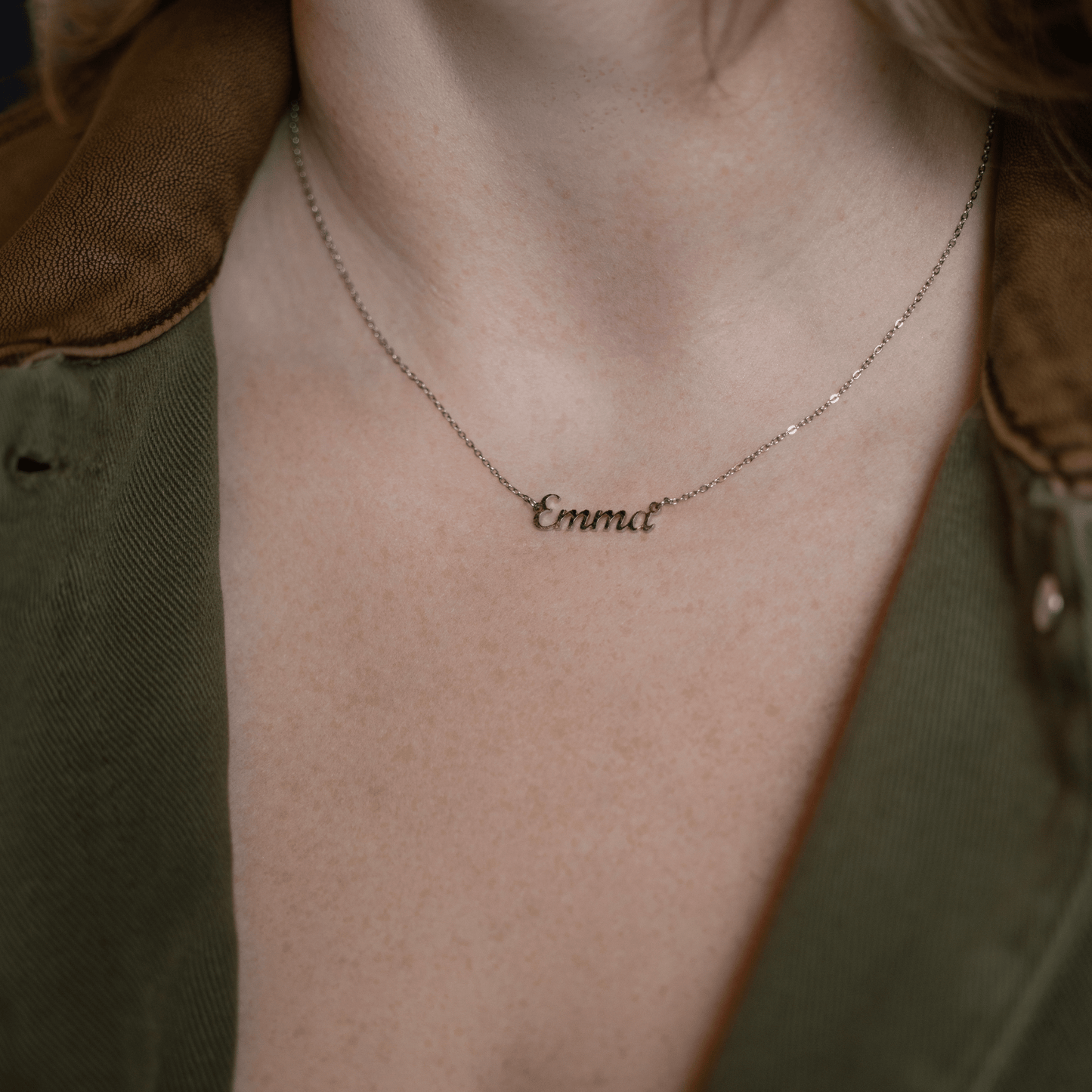 woman wearing a personalized silver name necklace featuring the name Emma in elegant script on a delicate chain.