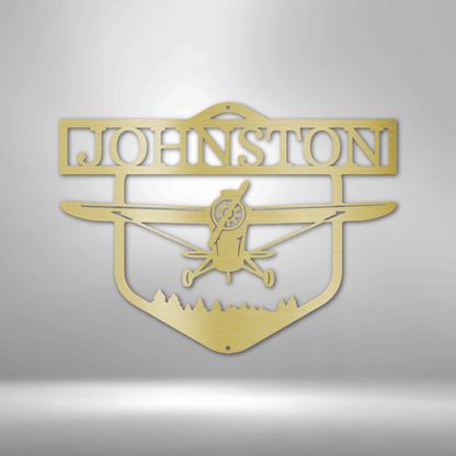 Decorative metal sign with airplane silhouette and 'Johnston' text on a white brick wall background