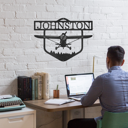 Decorative metal sign with airplane silhouette and 'Johnston' text on a white brick wall background With man sitting