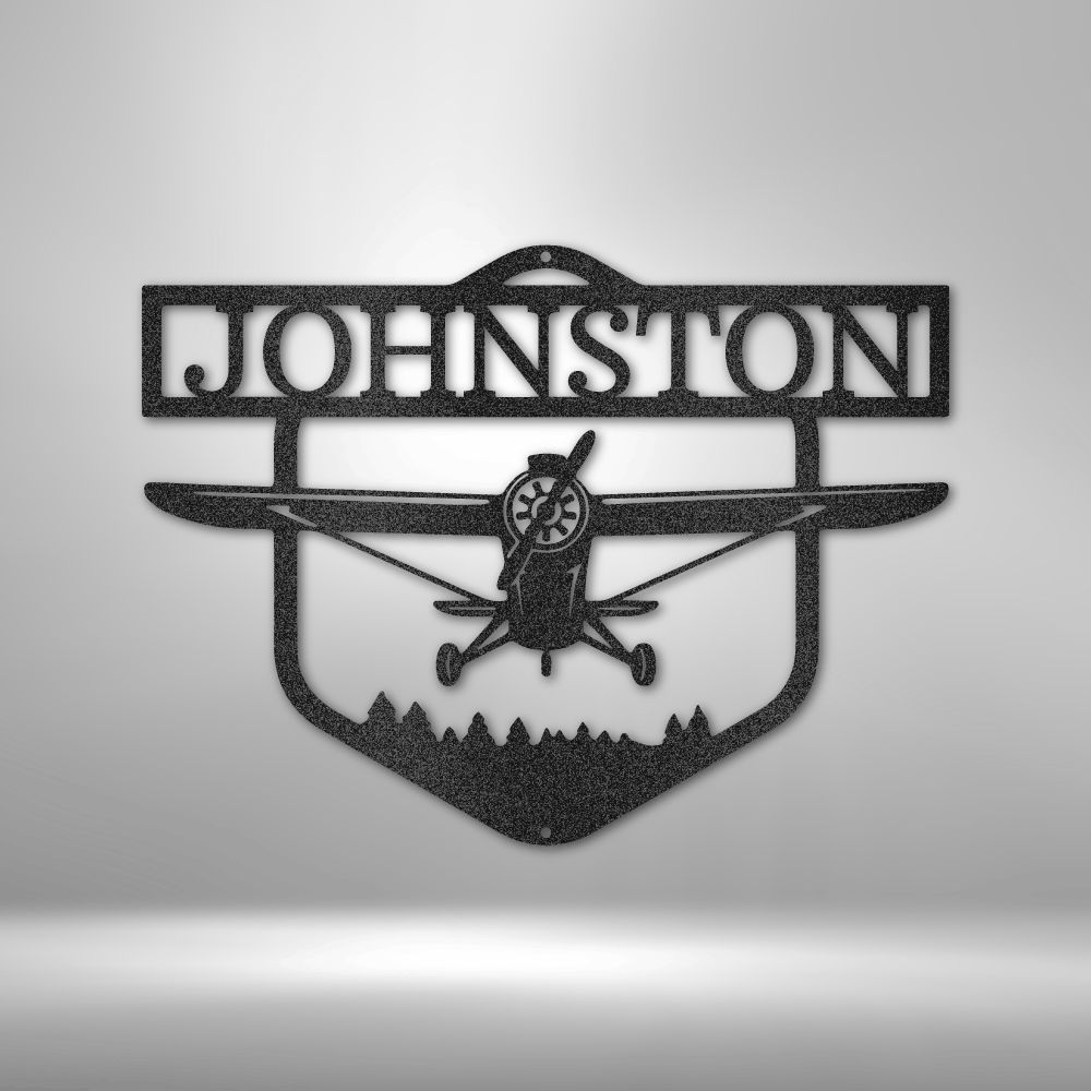 Decorative metal sign with airplane silhouette and 'Johnston' text on a white wall background
