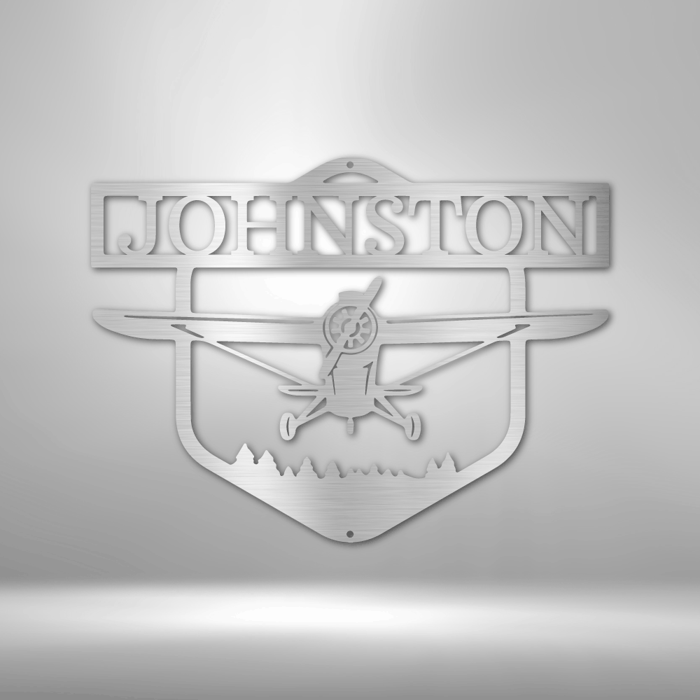 Decorative metal sign with airplane silhouette and 'Johnston' text on a white wall background