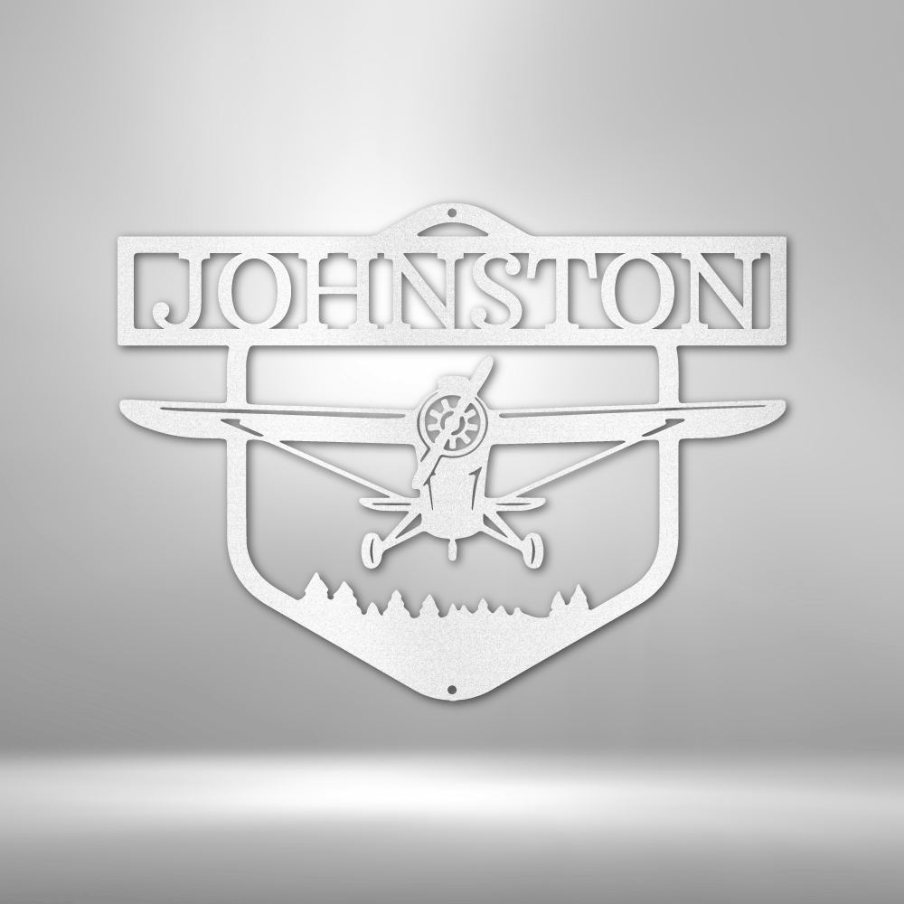 Decorative metal sign with airplane silhouette and 'Johnston' text on a white wall background