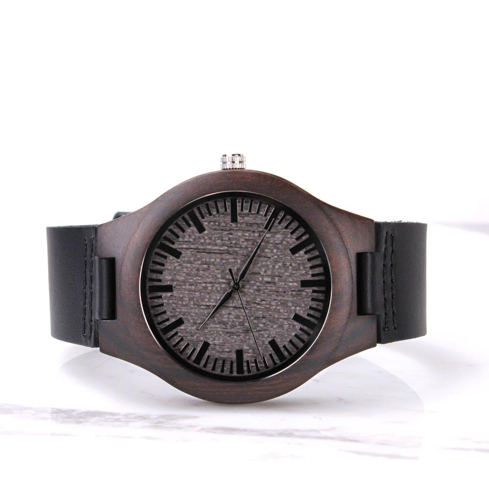 Dark wood men’s wristwatch with black leather strap and textured gray dial on white background