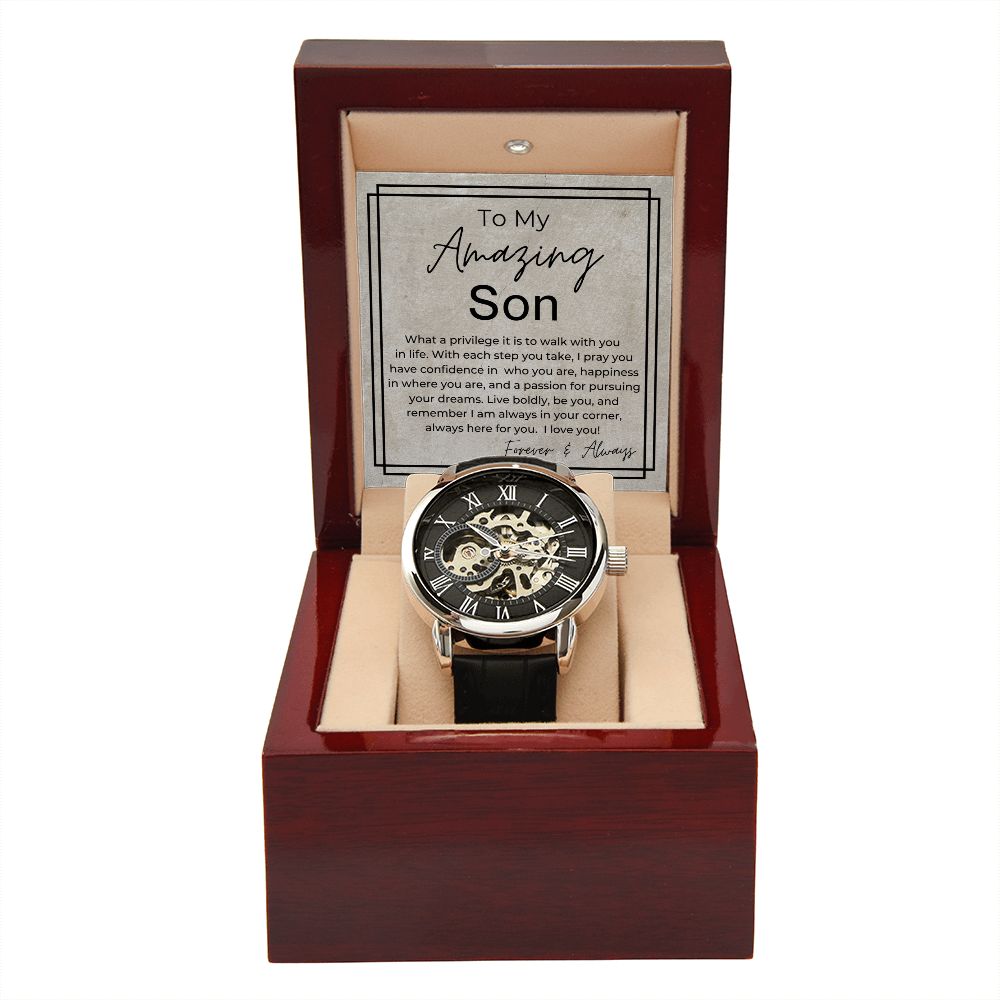 Skeleton mechanical watch with Roman numeral dial and black leather strap alongside heartfelt gift message card