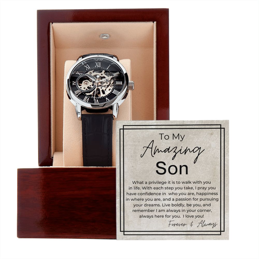 Skeleton mechanical watch with Roman numeral dial and black leather strap alongside heartfelt gift message card