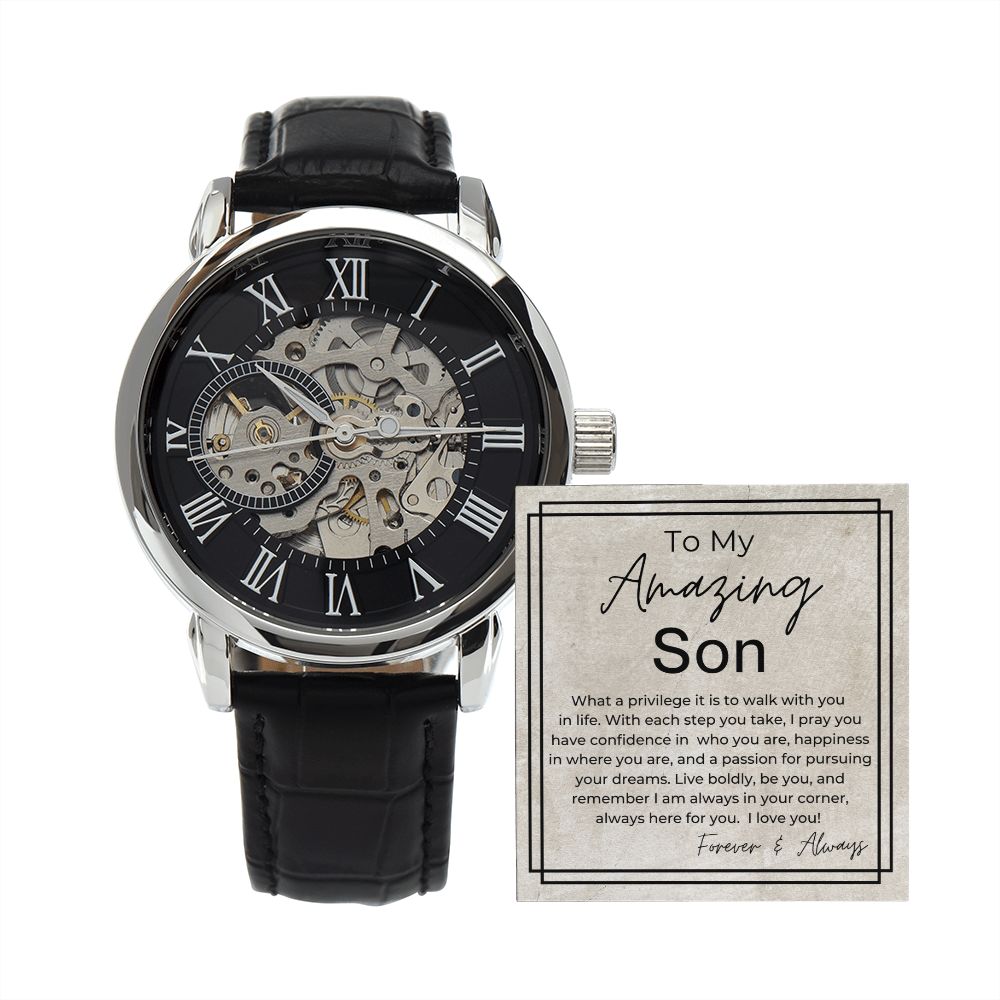 Skeleton mechanical watch with Roman numeral dial and black leather strap alongside heartfelt gift message card